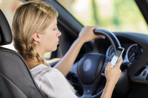 woman looking at her cell phone while driving